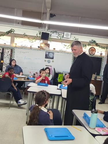 Fr. Robert Johnson visits with students during Catholic Schools Week at St Frances Cabrini School